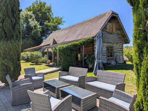 une terrasse avec des chaises et des tables en osier ainsi qu'une maison dans l'établissement L'Isba, à Sarlat-la-Canéda