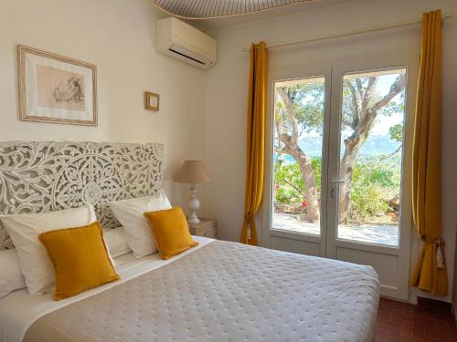 a bedroom with a bed with yellow pillows and a window at Kallinera in Porto-Vecchio