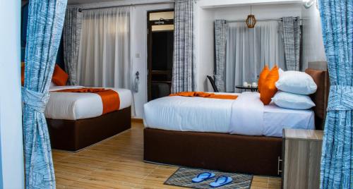 a hotel room with two beds with orange pillows at wonderland Destinations Resort, Naivasha in Naivasha