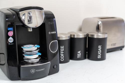 a row of four black and silver cups next to a toaster at Family,Cosy 2 Bedroom Apartment with Garden Close to Town, Seafront, Hospital, Free Parking in Eastbourne