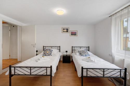 due letti in una stanza con pareti bianche di M B Homes Schlatt Fewo 1 a Hechingen