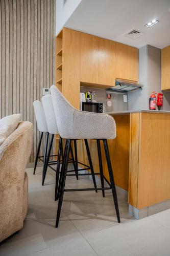 a kitchen with two chairs and a counter at 1BR Mamsha Nest with balcony by BlueCloud Holidays in Sharjah Intl