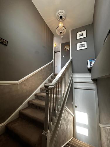 a hallway with stairs with a chandelier at Stylish City Centre Apartment in Bath