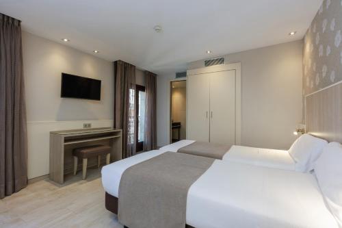 a hotel room with two beds and a television at Hotel Santa Marta in Barcelona