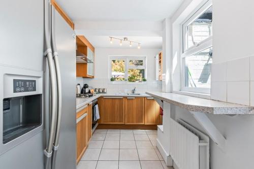 a kitchen with wooden cabinets and a refrigerator at 2 Bed House ,Close to Bromley South Station , Free Parking in Bromley