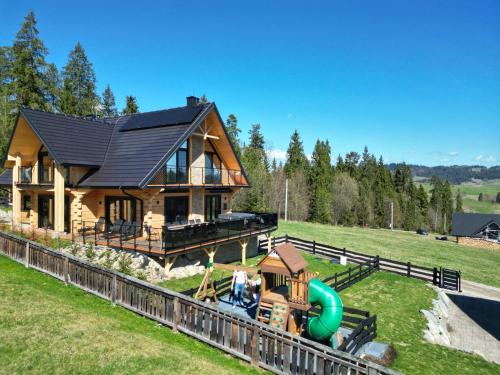 a log house with a playground in front of it at LK Forest Villa luksusowe domy z basenem z jacuzzi, sauną, grotą solną, salą bilardową i ogrodem in Łapsze Niżne