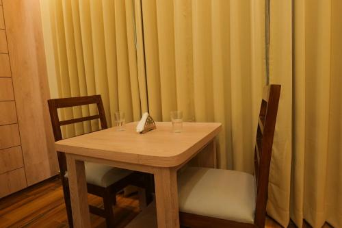 a wooden table with two glasses and a napkin at Hotel Mantavya in Kakarmatha