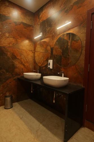 a bathroom with two sinks and two mirrors at Hotel Mantavya in Kakarmatha