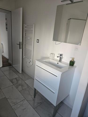 une salle de bain blanche avec un lavabo et un miroir dans l'établissement peaceful new home T2, à La Rochelle