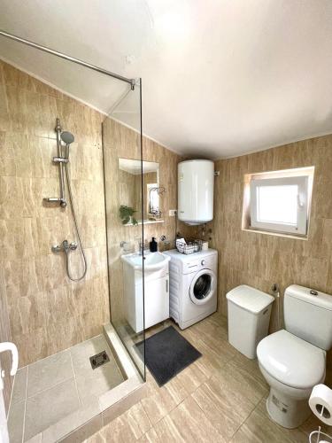 a bathroom with a shower toilet and a washing machine at Apartments Pribilovic in Budva