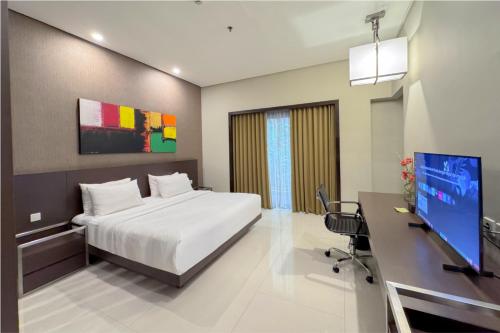 a bedroom with a bed and a desk with a computer at Savana Hotel & Convention Malang in Malang