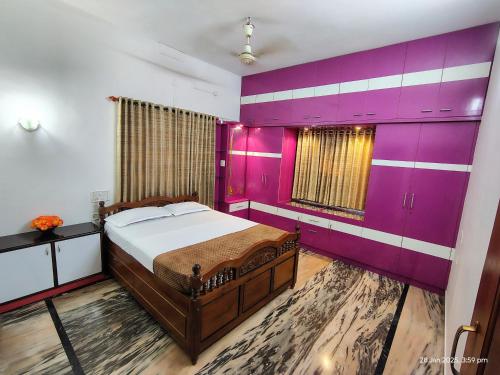 a bedroom with a bed and a purple wall at Kinaara Homestay Thottam Malpe Beach Udupi in Malpe