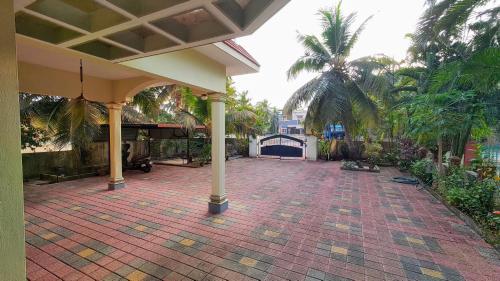 an outdoor patio with a pavilion and palm trees at Kinaara Homestay Thottam Malpe Beach Udupi in Malpe