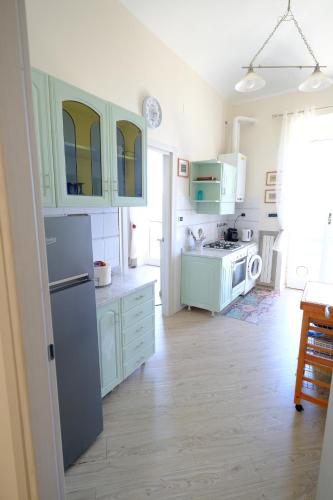 a kitchen with green cabinets and a white refrigerator at La casa di sotto by PortofinoVacanze in Camogli