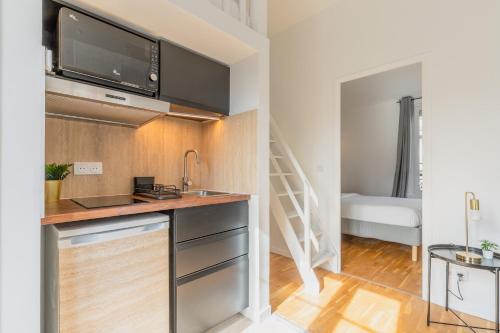 Il comprend une cuisine avec un évier et une télévision murale. dans l'établissement Brand New - Exquisite and Sunny Parisian Loft, à Paris