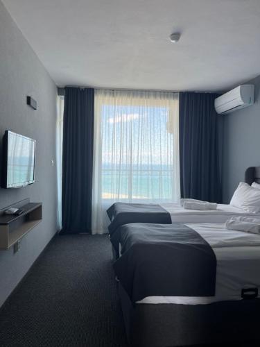 a hotel room with three beds and a window at Family Hotel Sunrise in Lozenets