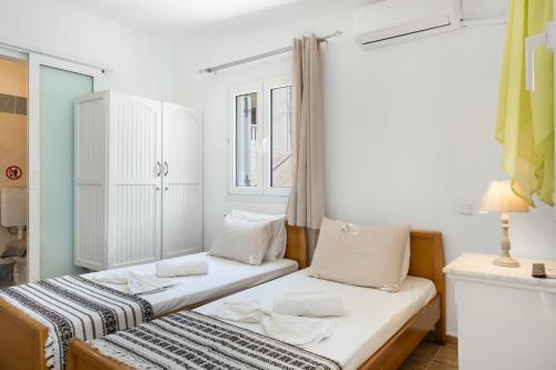 a room with two beds and a window at Ilias Studios Sevasti Kalymnos in Panormos Kalymnos