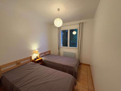 deux lits dans une chambre avec une fenêtre dans l'établissement Charmante villa avec terrasse près de la plage - FR-1-831-11, à Biscarrosse