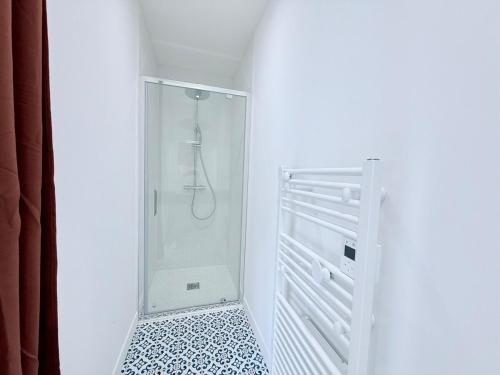 La salle de bains est pourvue d'une douche blanche avec une porte en verre. dans l'établissement 1753-1 L'atelier du gabier, à Rochefort