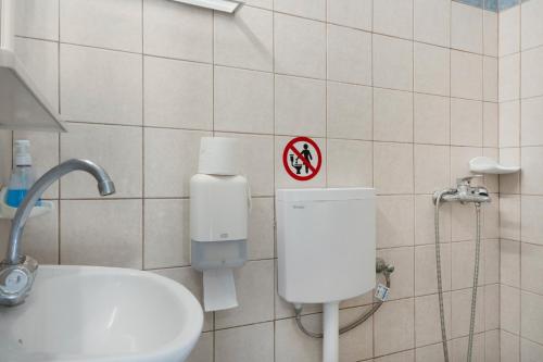 a bathroom with a toilet and a sink with a sign at Ilias Studios Sevasti Kalymnos in Panormos Kalymnos