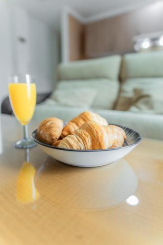 a bowl of croissants and a glass of orange juice on a table at Apartamentos Turisticos Las Yucas in Torre del Mar