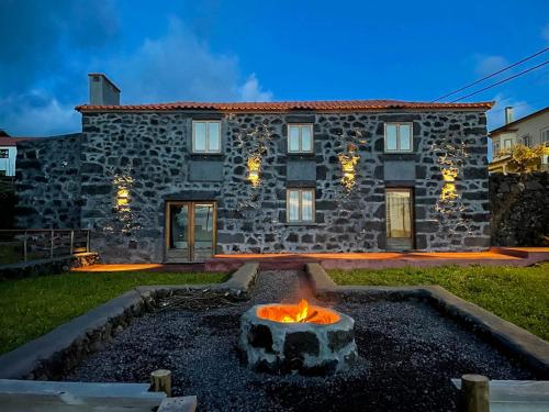 a stone house with a fire pit in front of it at Quinta do Almanac in Queimada