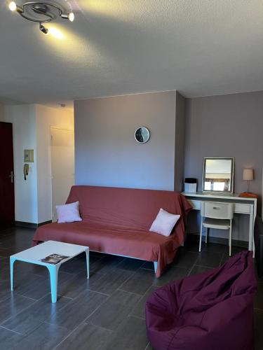 un salon avec un canapé rouge et une table dans l'établissement T2 + Cabine à Canet Plage – 4 Couchages, Terrasse, à 100 m de la Mer, à Canet