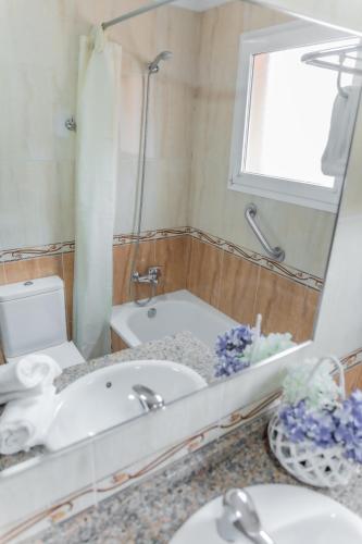 a bathroom with a tub and a sink and a mirror at Apartamentos Turisticos Las Yucas in Torre del Mar