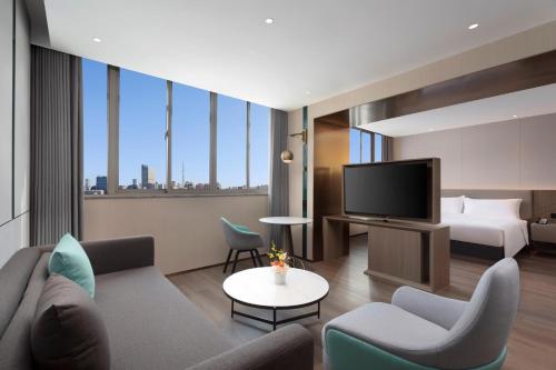 a hotel room with a couch and a bed and a television at Holiday Inn Shanghai Jing'an in Shanghai