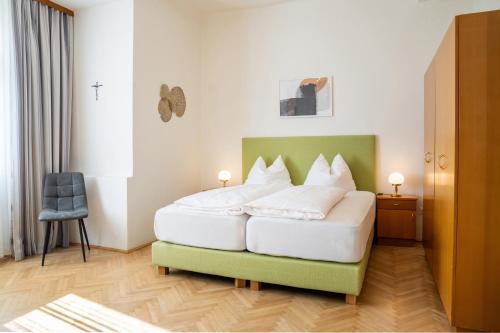 a bedroom with a large white bed with a green headboard at Johannes Schlössl - Gästehaus der Pallottiner am Mönchsberg in Salzburg