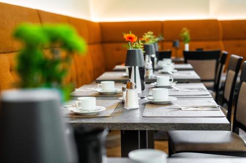 a row of long tables in a restaurant with flowers at Johannes Schlössl - Gästehaus der Pallottiner am Mönchsberg in Salzburg
