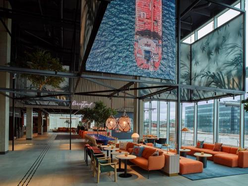 a lobby of a building with orange chairs and tables at Scandic Göteborg Central in Gothenburg