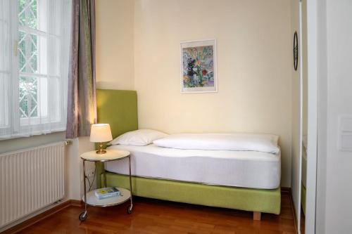 a small bed in a small room with a lamp at Johannes Schlössl - Gästehaus der Pallottiner am Mönchsberg in Salzburg