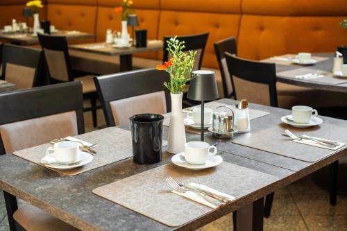 a table with plates and utensils and flowers on it at Johannes Schlössl - Gästehaus der Pallottiner am Mönchsberg in Salzburg