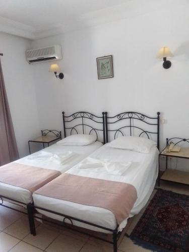 a bedroom with two beds with white sheets and a fan at Hotel Les Citronniers Hammamet in Hammamet