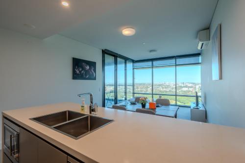 a kitchen with a sink and a view of a living room at Modern Apartment with City View at Sydney Olympic Park in Sydney