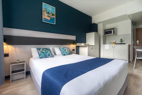 une chambre avec un grand lit avec un mur bleu dans l'établissement City Résidence Strasbourg Centre, à Strasbourg