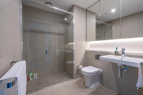 a bathroom with a shower and a toilet and a sink at Modern Apartment with City View at Sydney Olympic Park in Sydney