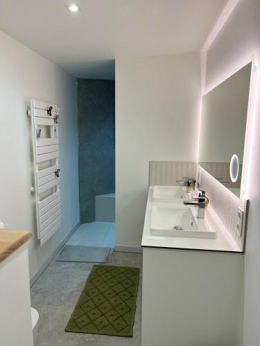 une salle de bain blanche avec un lavabo et un miroir dans l'établissement Cyprès de l'Océan, à Angles