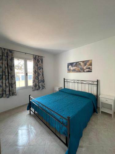 a bedroom with a bed with blue sheets and a window at Appartamento Gallospot in San Teodoro