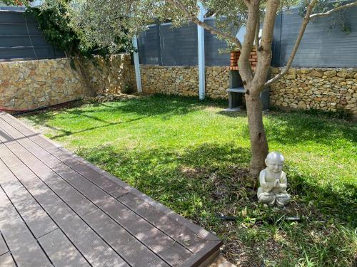 a statue sitting next to a tree in a yard at Vila Alegre in Fuzeta