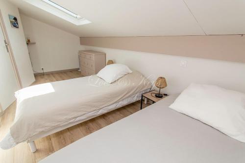deux lits dans une chambre aux murs blancs et au parquet dans l'établissement 4-person duplex, à Biscarrosse