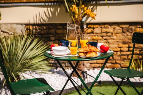 a table with a plate of food and glasses of orange juice at Appartement fraîchement rénovée - Jacuzzi au cœur de Caen in Caen