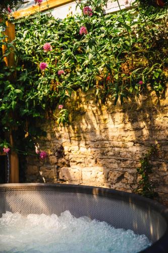 a garden tub with pink flowers on a stone wall at Appartement fraîchement rénovée - Jacuzzi au cœur de Caen in Caen