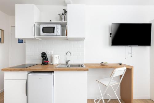 une cuisine blanche avec un évier et un micro-ondes dans l'établissement Roi Arthur, à Brest