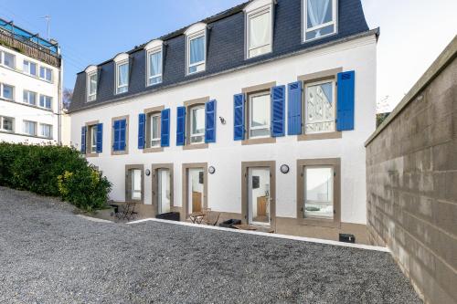 Un grand bâtiment blanc avec des fenêtres à volets bleus est disponible. dans l'établissement Roi Arthur, à Brest