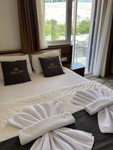 a bed with two towels on it with a window at Pamukkale Sahin Hotel in Pamukkale