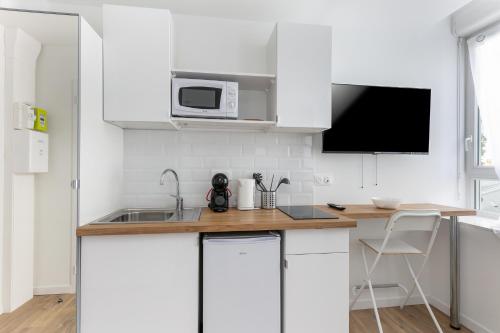 une cuisine avec des armoires blanches et un micro-ondes dans l'établissement Fée Viviane, à Brest