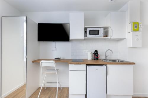 une cuisine blanche avec un évier et un micro-ondes dans l'établissement Fée Morgane, à Brest