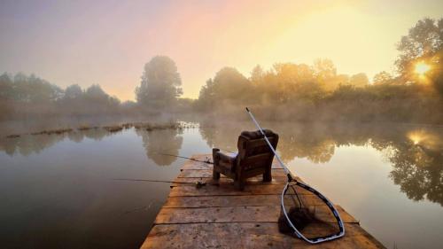 a chair sitting on a dock on a lake at Dworek Króla Stanisława - Apartament Malinowy in Węgorzewo
